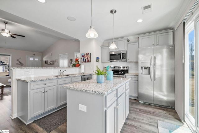 kitchen featuring backsplash, stainless steel appliances, sink, a center island, and hanging light fixtures