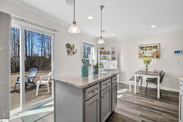 kitchen with dark hardwood / wood-style floors, gray cabinets, decorative light fixtures, a kitchen island, and light stone counters