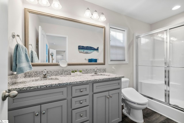 bathroom with a shower with door, vanity, hardwood / wood-style floors, and toilet