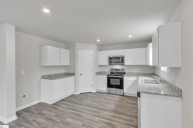 kitchen with light stone counters, stainless steel appliances, sink, light hardwood / wood-style flooring, and white cabinets