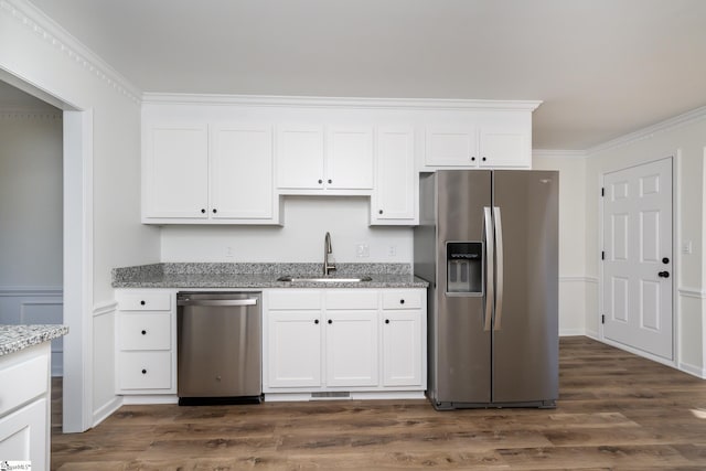 kitchen with light stone countertops, appliances with stainless steel finishes, ornamental molding, sink, and white cabinetry