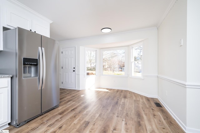 kitchen featuring white cabinetry, stainless steel fridge with ice dispenser, ornamental molding, and light hardwood / wood-style flooring