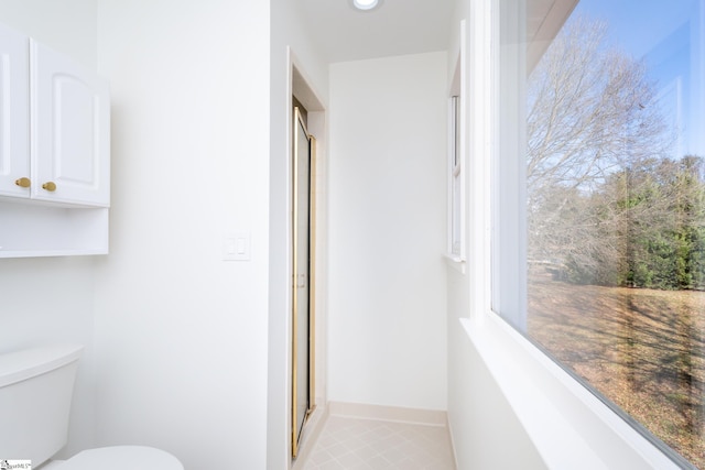 bathroom featuring tile patterned flooring, toilet, and a shower with door