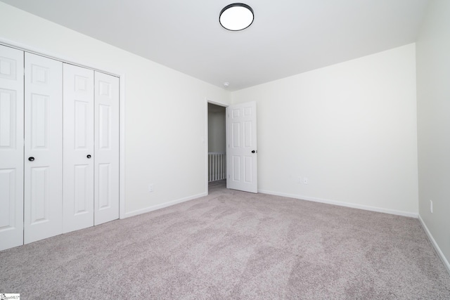 unfurnished bedroom featuring light carpet and a closet