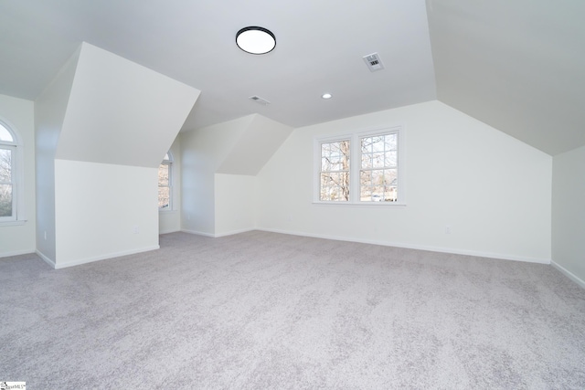 bonus room with light carpet and vaulted ceiling