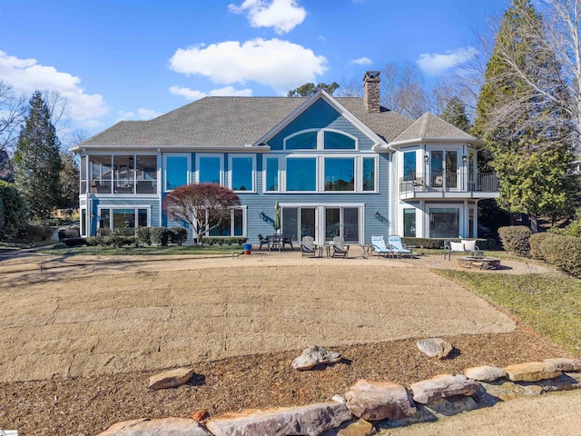 back of property with a lawn, a sunroom, a balcony, and a patio