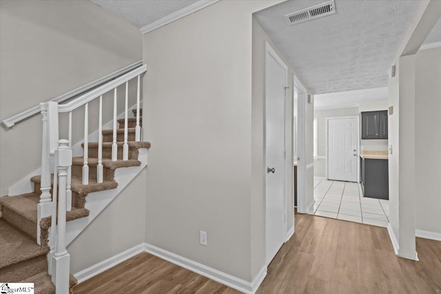 stairway featuring ornamental molding, a textured ceiling, and hardwood / wood-style flooring