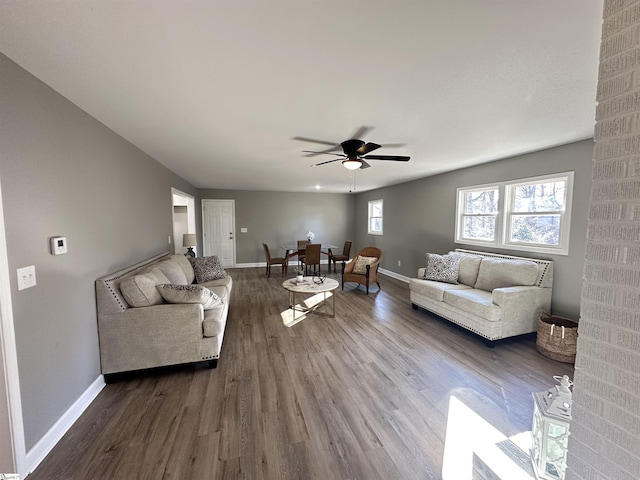 living area with dark wood finished floors, a ceiling fan, and baseboards