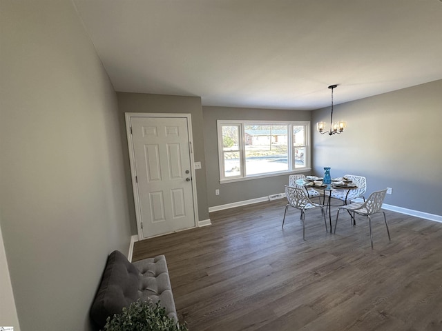 dining room featuring dark wood-style flooring, visible vents, a notable chandelier, and baseboards