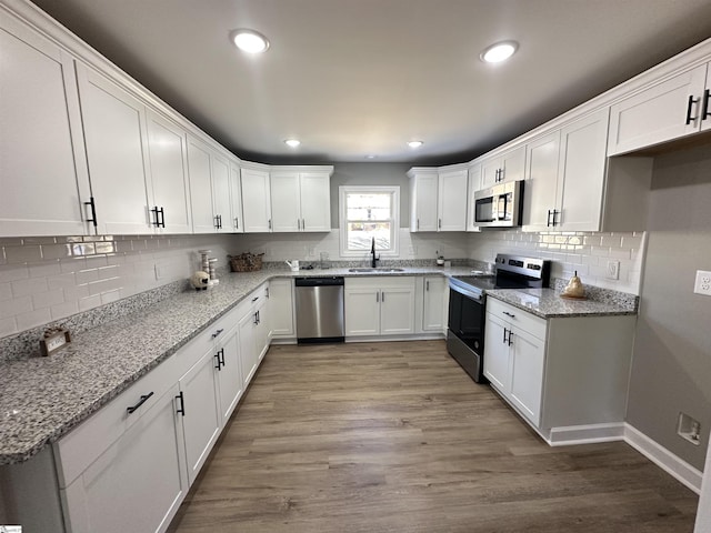 kitchen featuring light wood-style flooring, recessed lighting, stainless steel appliances, a sink, and white cabinetry