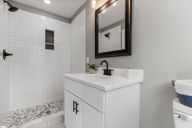 bathroom with toilet, marble finish floor, tiled shower, and vanity