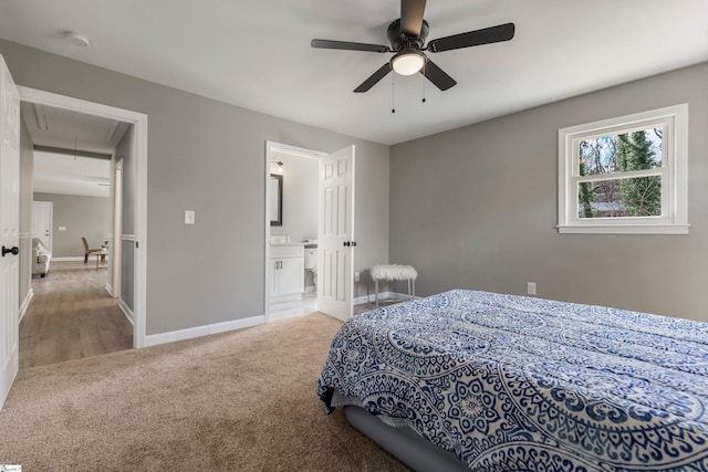 carpeted bedroom with ensuite bath, attic access, baseboards, and a ceiling fan