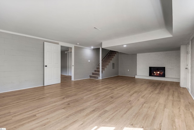 unfurnished living room featuring light wood-type flooring, a fireplace, stairway, and recessed lighting