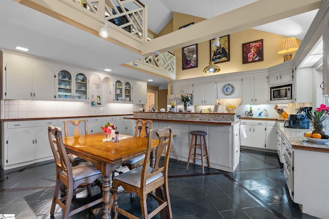 dining space featuring high vaulted ceiling