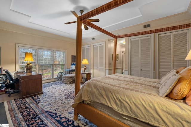 bedroom with ceiling fan, ornamental molding, and two closets