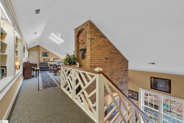 hallway with carpet floors and lofted ceiling with skylight