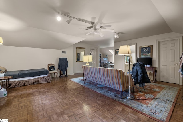 living room featuring dark parquet floors, ceiling fan, and vaulted ceiling