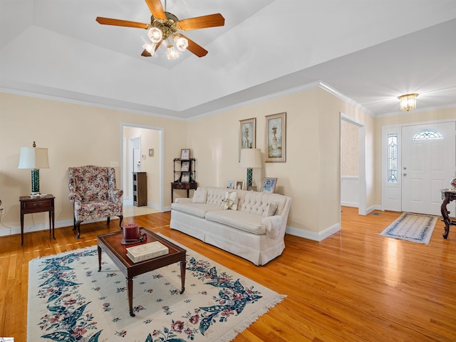 living room with a raised ceiling, ceiling fan, hardwood / wood-style floors, and crown molding