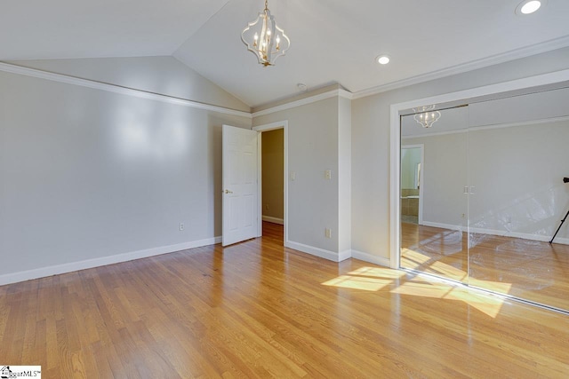 unfurnished bedroom featuring a chandelier, light hardwood / wood-style floors, lofted ceiling, a closet, and ornamental molding