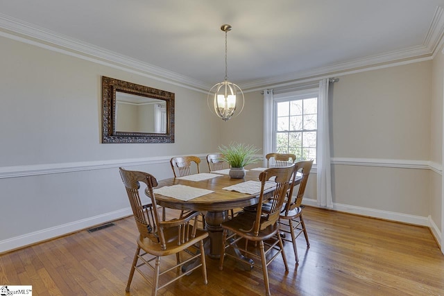 dining area with a notable chandelier, light hardwood / wood-style floors, and ornamental molding