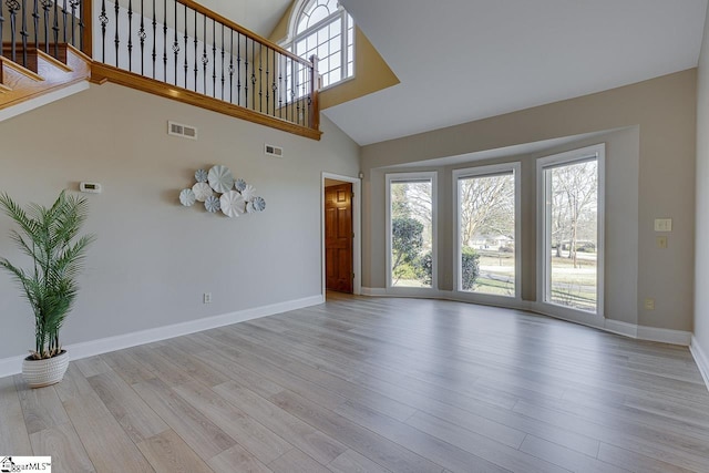 unfurnished living room featuring a towering ceiling and light hardwood / wood-style flooring