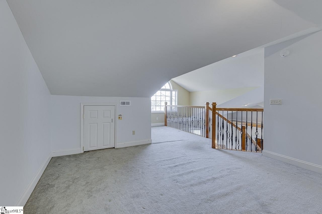 additional living space featuring lofted ceiling and light carpet