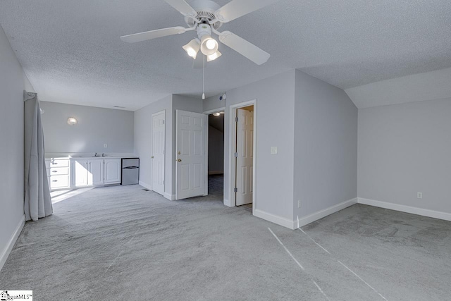 additional living space featuring light carpet, sink, vaulted ceiling, ceiling fan, and a textured ceiling