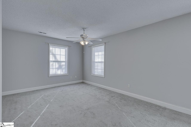 carpeted empty room with ceiling fan and a textured ceiling