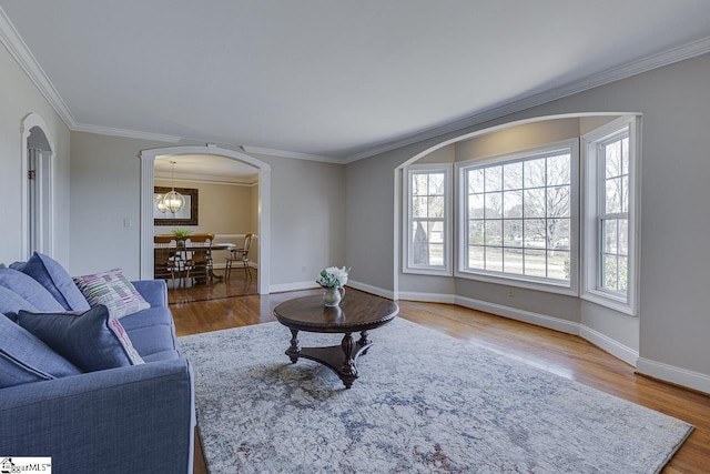 living room featuring wood-type flooring, crown molding, and a notable chandelier