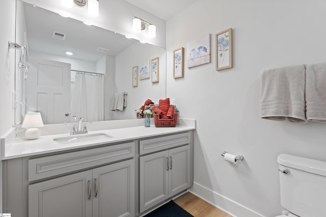 bathroom featuring walk in shower, vanity, wood-type flooring, and toilet