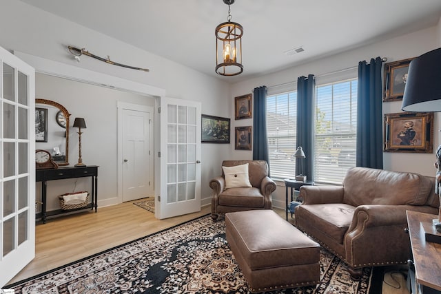 living area featuring a notable chandelier, light wood-type flooring, and french doors