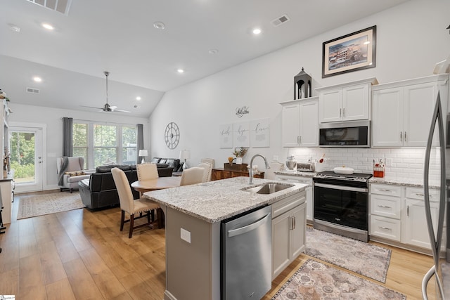 kitchen with white cabinetry, sink, stainless steel appliances, and a center island with sink