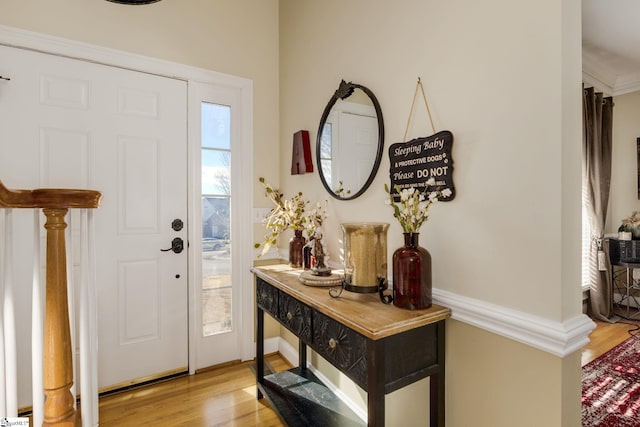 entrance foyer featuring ornamental molding and light hardwood / wood-style flooring