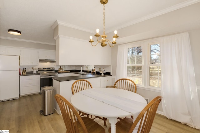 dining room featuring a notable chandelier, light hardwood / wood-style floors, ornamental molding, and sink