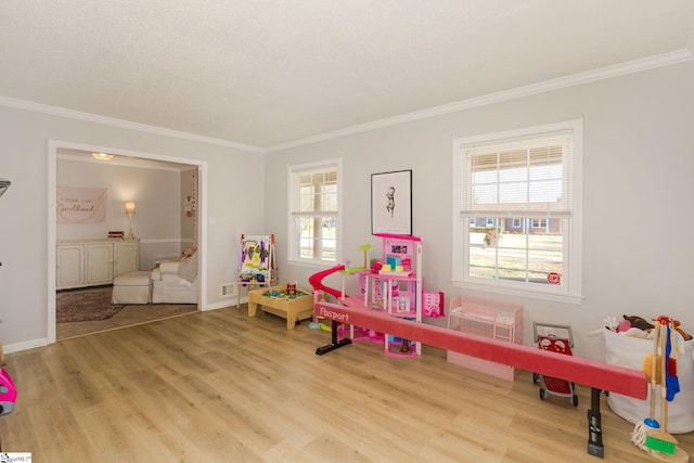 recreation room with ornamental molding and light wood-type flooring