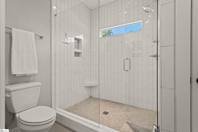 bathroom with tile patterned flooring, a shower with shower door, and toilet