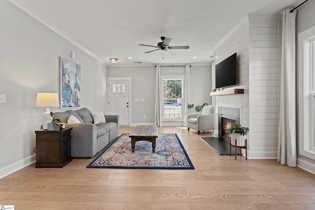 living room featuring ceiling fan, a fireplace, light hardwood / wood-style flooring, and ornamental molding