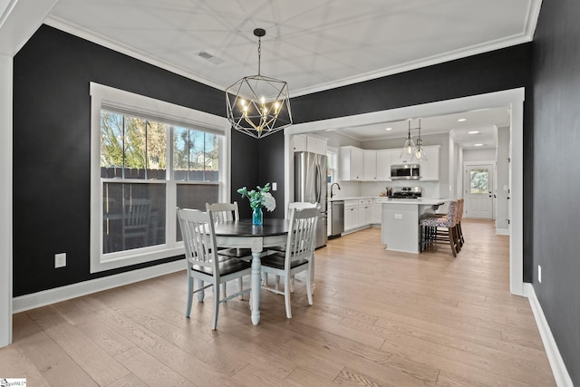 dining area featuring light wood-type flooring, ornamental molding, and a chandelier