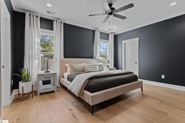 bedroom featuring ceiling fan, light hardwood / wood-style floors, ornamental molding, and multiple windows