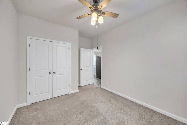 unfurnished bedroom with a closet, light colored carpet, and ceiling fan