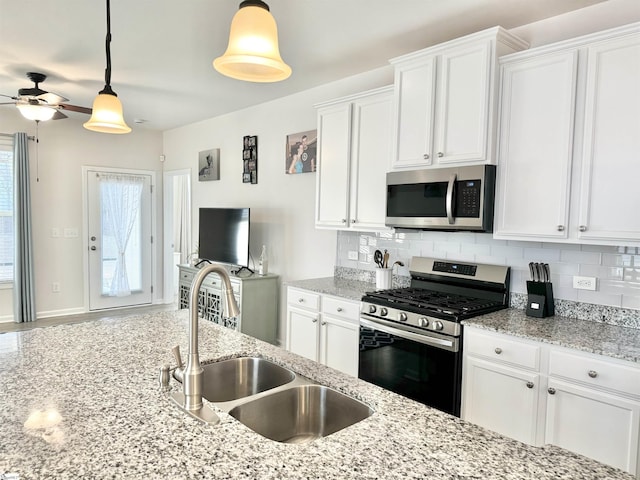 kitchen with sink, backsplash, pendant lighting, white cabinets, and appliances with stainless steel finishes