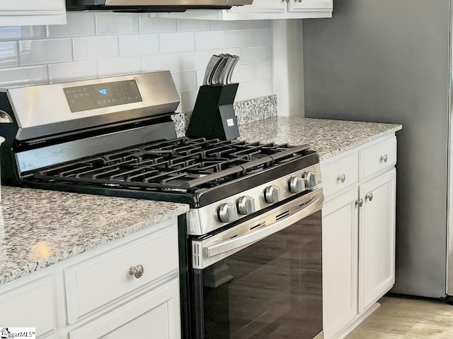 kitchen featuring stainless steel range with gas cooktop, white cabinets, and light stone counters