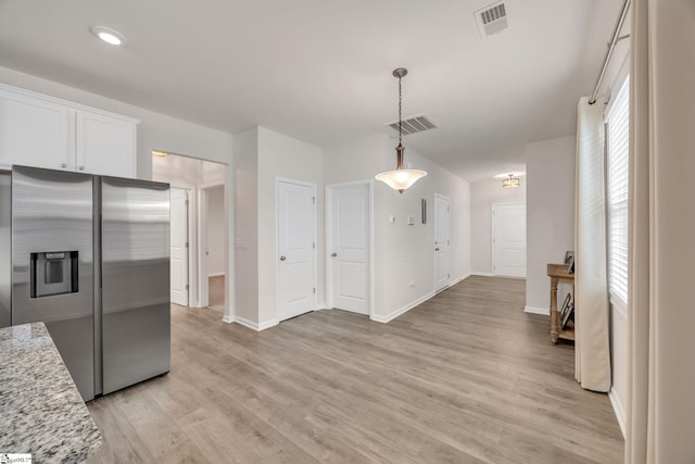 kitchen with light stone counters, light hardwood / wood-style flooring, stainless steel fridge with ice dispenser, white cabinetry, and hanging light fixtures