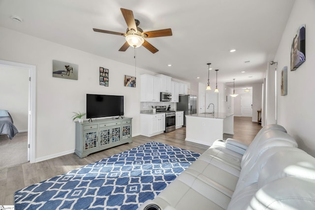 living room featuring hardwood / wood-style floors, ceiling fan, and sink