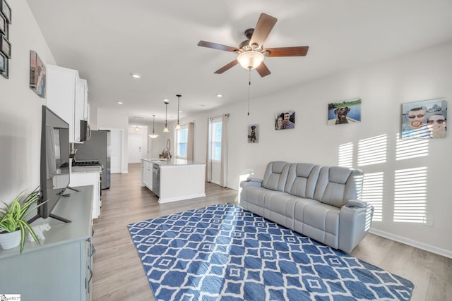 living room with ceiling fan, sink, and light hardwood / wood-style floors