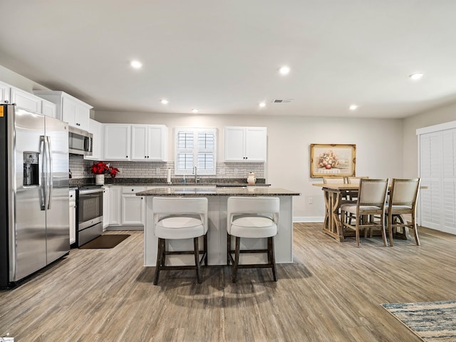 kitchen featuring light hardwood / wood-style floors, a kitchen island, white cabinetry, and stainless steel appliances