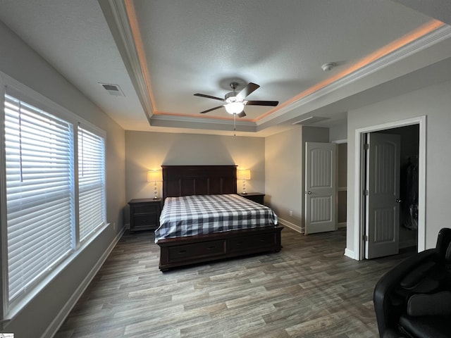 bedroom with hardwood / wood-style floors, a tray ceiling, ceiling fan, and crown molding