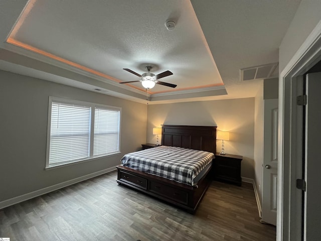 bedroom with a raised ceiling, ceiling fan, crown molding, and wood-type flooring