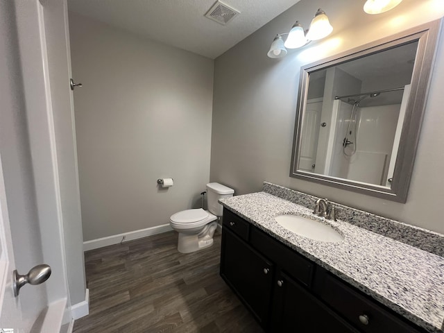 bathroom with walk in shower, hardwood / wood-style floors, a textured ceiling, toilet, and vanity