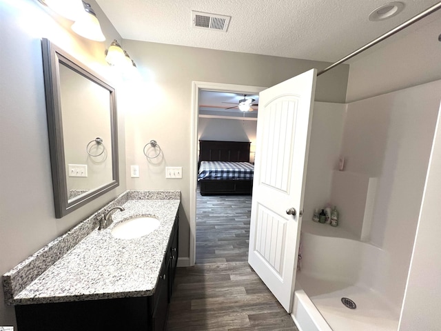 bathroom featuring walk in shower, a textured ceiling, vanity, ceiling fan, and wood-type flooring